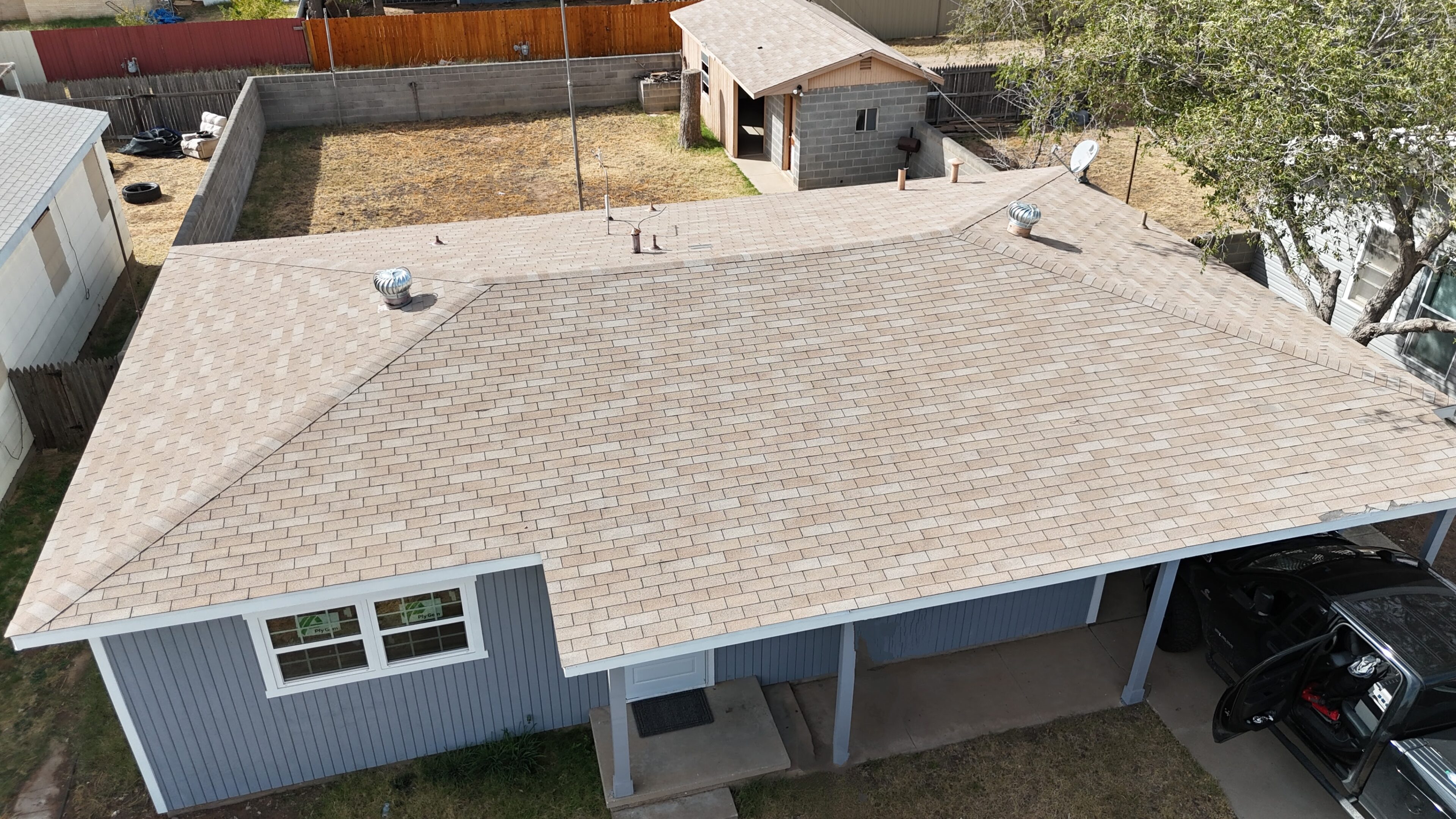 Aerial view of a house roof with light-colored shingles and chimneys.