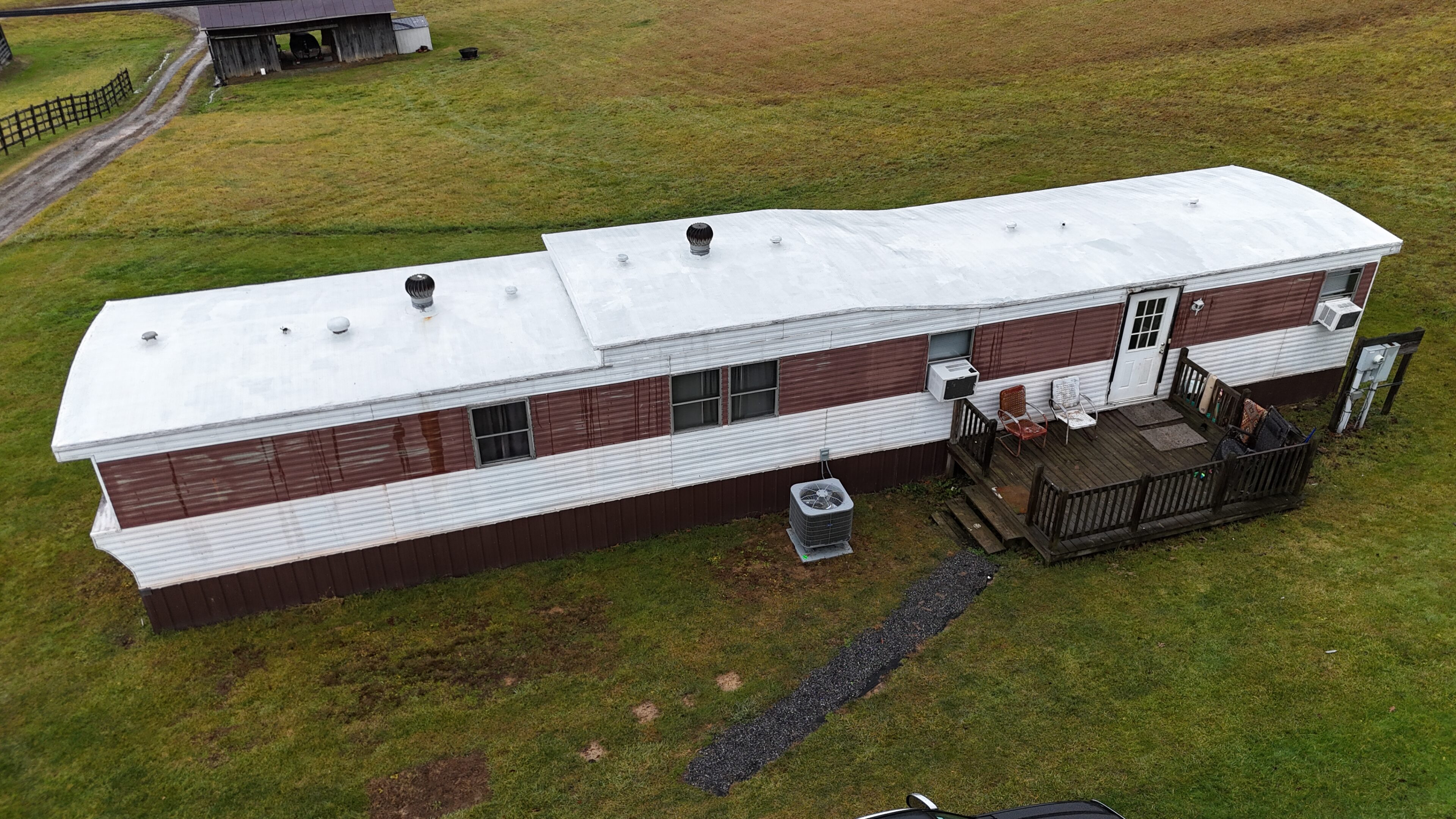 A long, white, rectangular building with a flat roof on a grassy field.