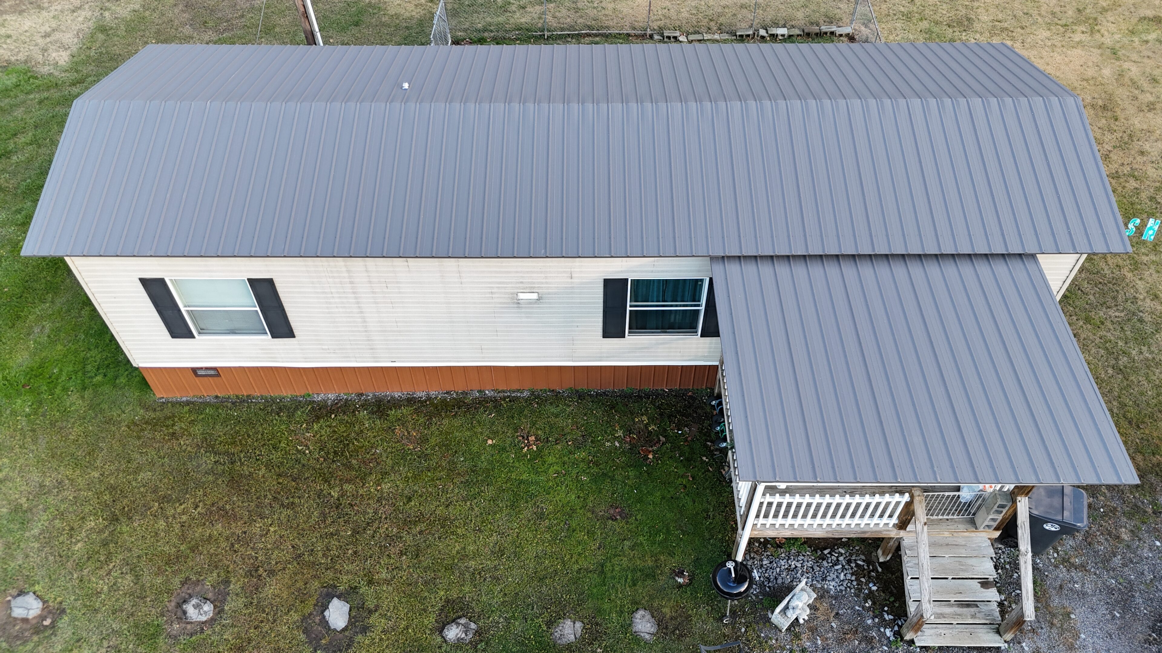 Aerial view of a house with a metal roof and green lawn.