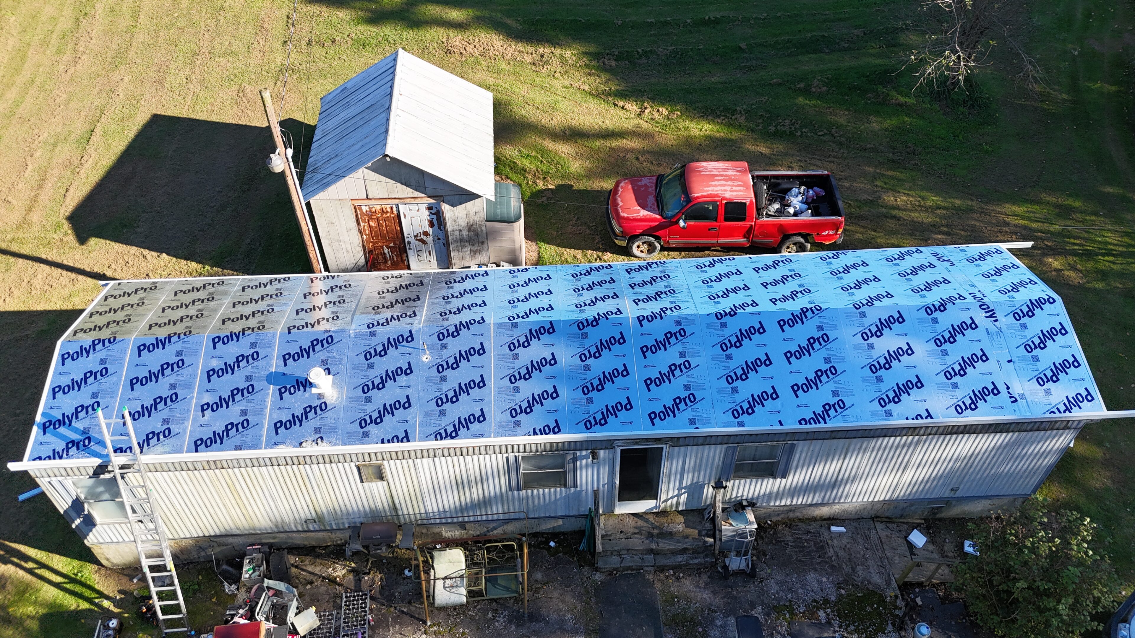 Aerial view of a partially constructed building with a blue roof and nearby red truck.